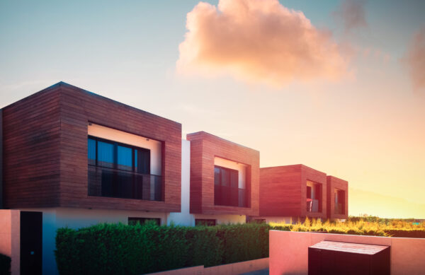 Modern houses with green plant wall and pink cloud in sunrise sky on background. Actual eco architecture